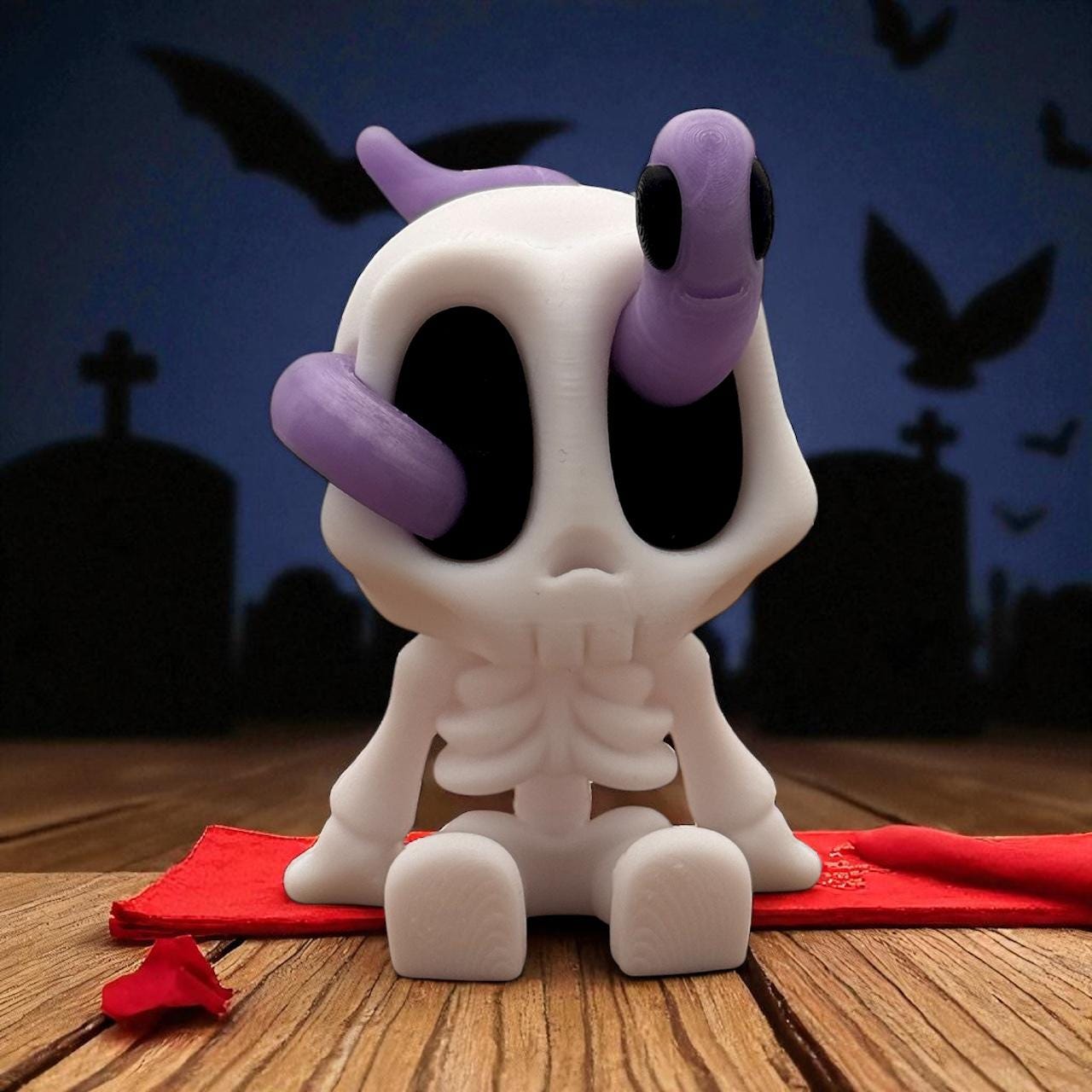 Blob Skeleton Figur als Halloween-Deko, weiße Skelettfigur mit schwarzem Gesicht und lila Wurm am Kopf, neben Maßangabe 7,6 cm groß, 3D-gedruckt.