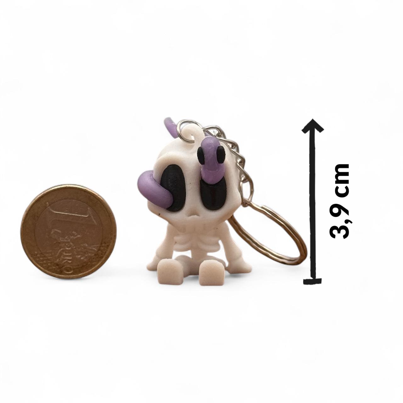 Skelett-Blob-Schlüsselanhänger (weiß/lila) auf weißem Hintergrund, Höhe ca. 3,9 cm; Euro-Münze zum Größenvergleich, Pfeil-Maßangabe, 3D-Druck.