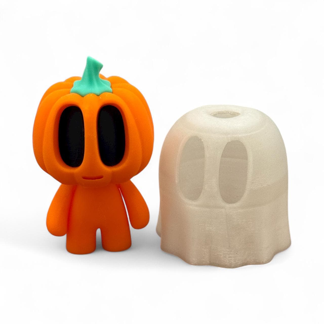 Blob Pumpkin Figur als Halloween-Deko, orangefarbener Kürbis mit schwarzem Gesicht, neben einem abnehmbaren Geister-Überwurf in Weiß, 3D-gedruckt.