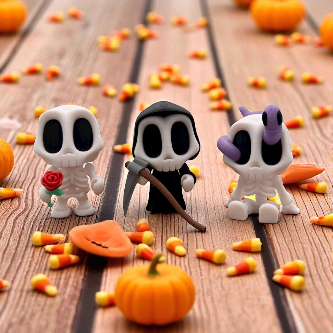 Blob Skeleton Figuren als Halloween-Deko, drei weiße Skelett-Blobs mit unterschiedlichen Accessoires – Rose, Sense und lila Schleife – auf Holztisch mit Kürbissen und Süßigkeiten, 3D-gedruckt.