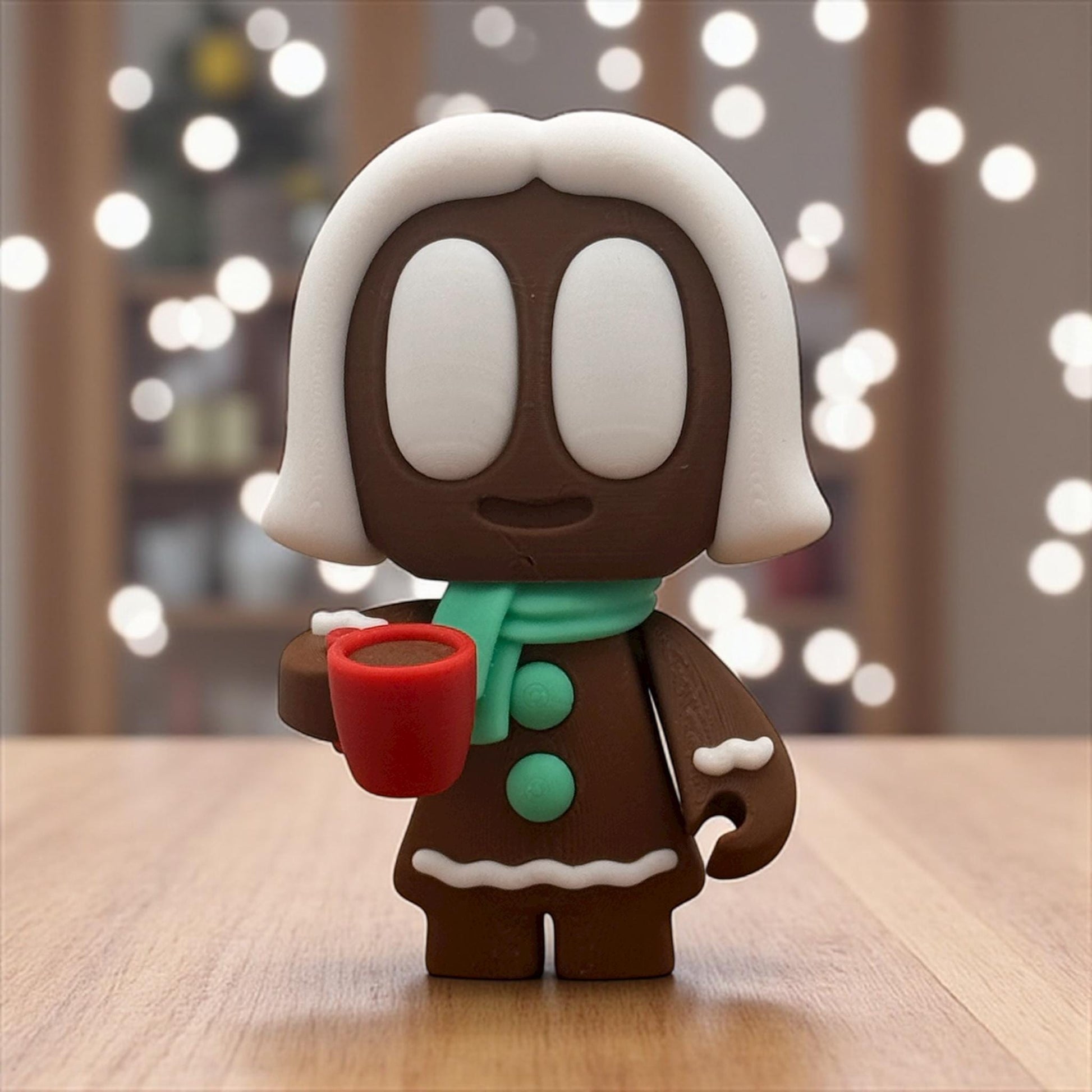Lebkuchen-Blob mit weißer Zuckerguss-Haube hält rote Tasse – 3D-gedruckte Weihnachtsfigur auf Holztisch, Nahaufnahme.